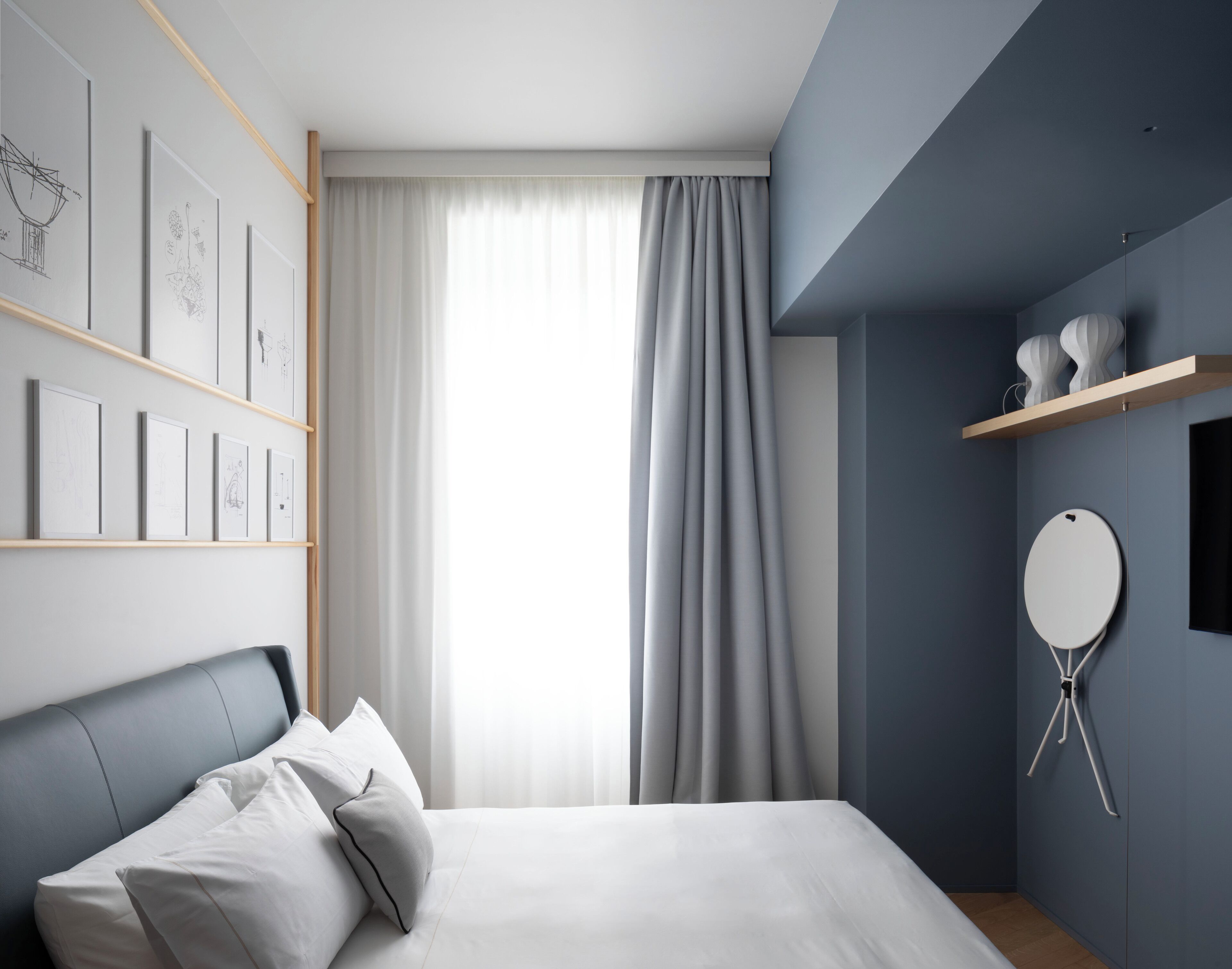 Una camera da letto moderna con un letto, una mensola a parete e uno specchio rotondo.