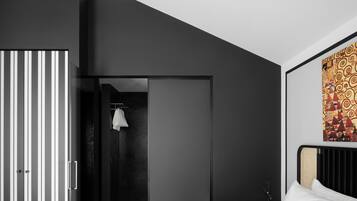 A modern bedroom with a bed, a wardrobe, and a shower area.