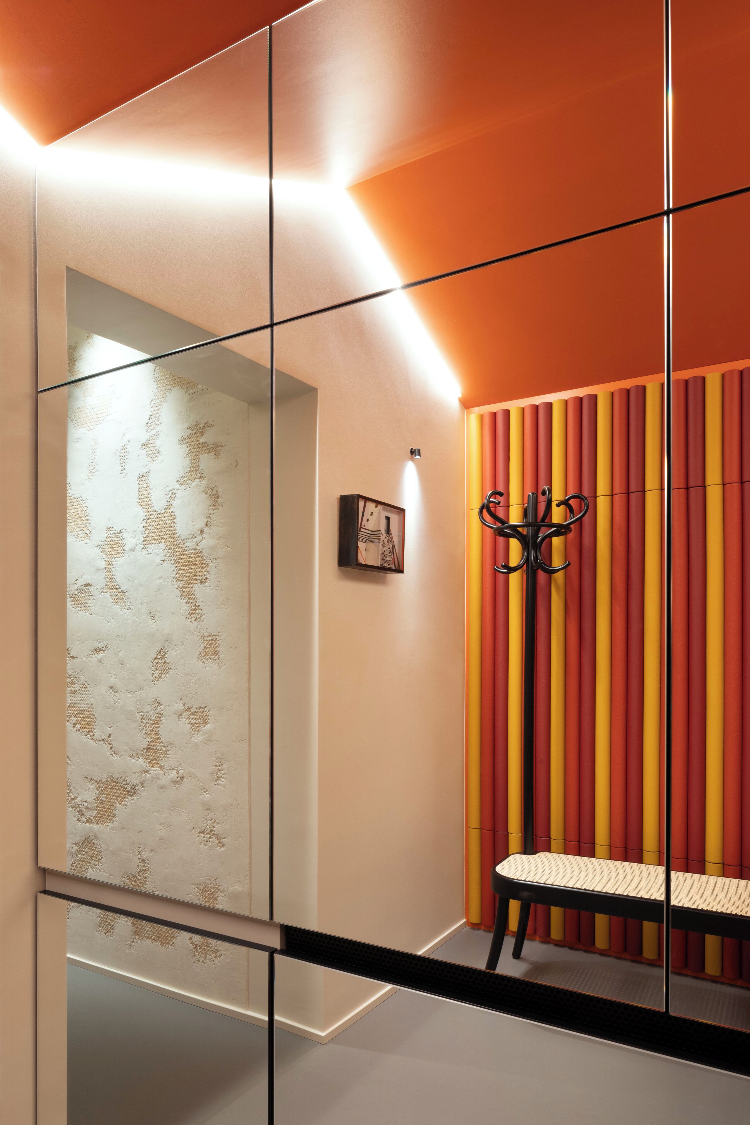 Ein modernes Interieur mit einer Glastrennwand, einer Bank und einer Wand mit vertikalen Streifen.