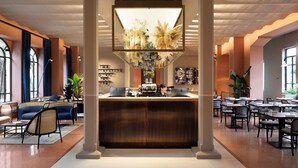 En moderne hotellobby med reception, siddeområde og store vinduer.
