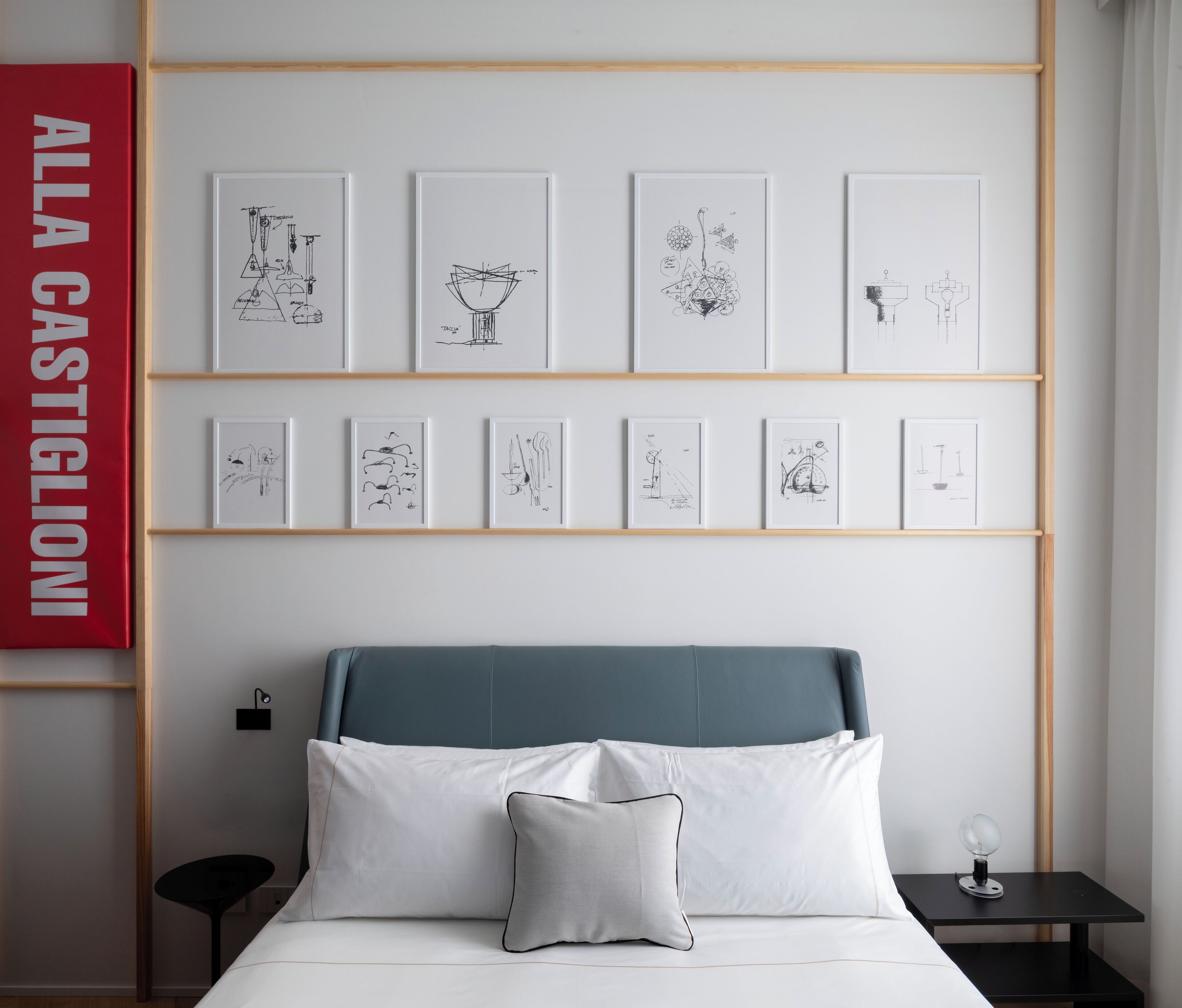 Une chambre à coucher avec un lit, des oreillers, une table de chevet, une lampe et des œuvres d’art encadrées accrochées au mur.