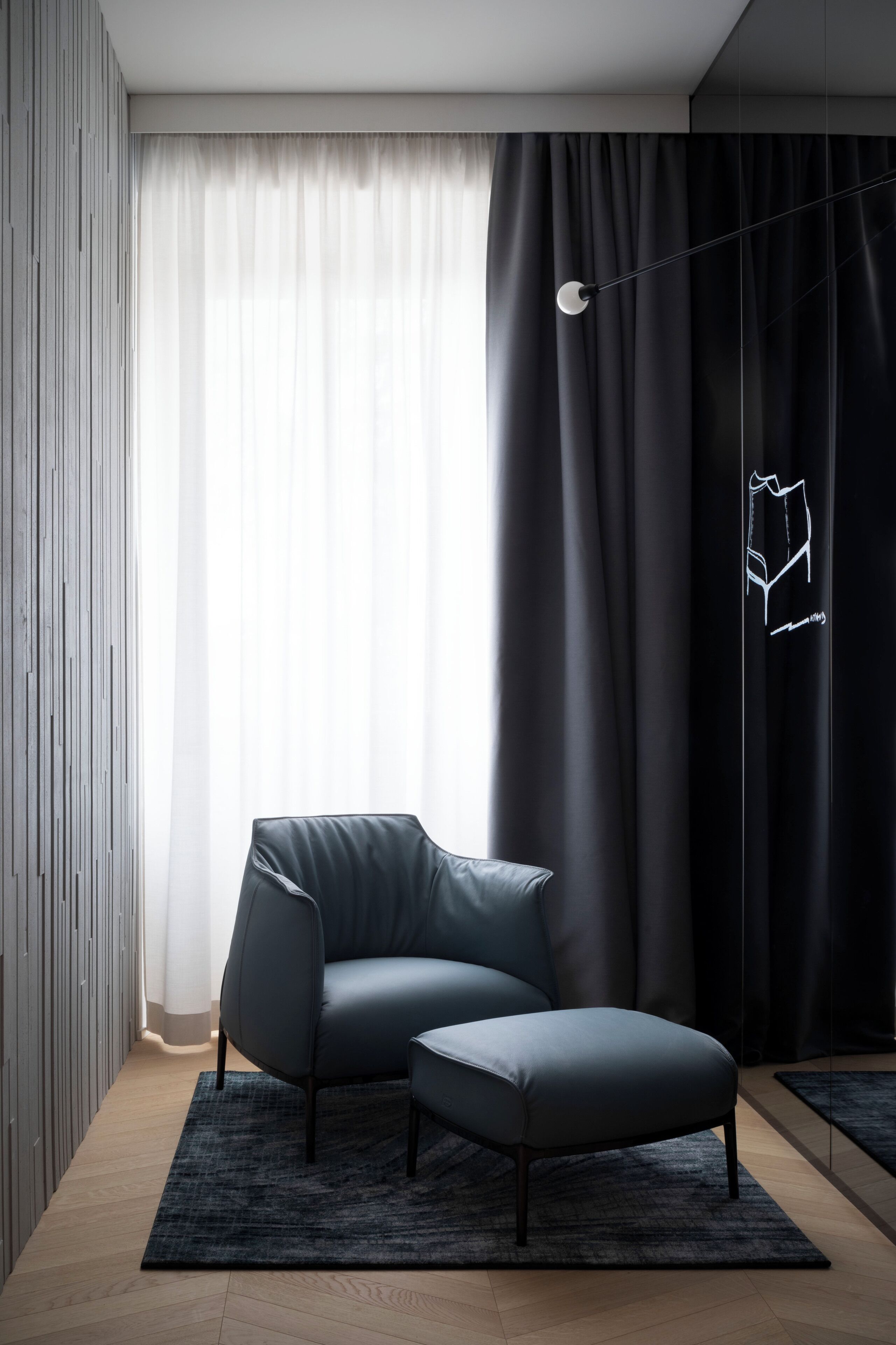 Ein modernes Wohnzimmer mit einem dunkelbraunen Ledersofa und Hocker, einem gemusterten Teppich und schlichter Einrichtung.