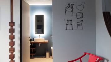 A modern interior with a wooden floor, a red chair, and a wall with sketches.