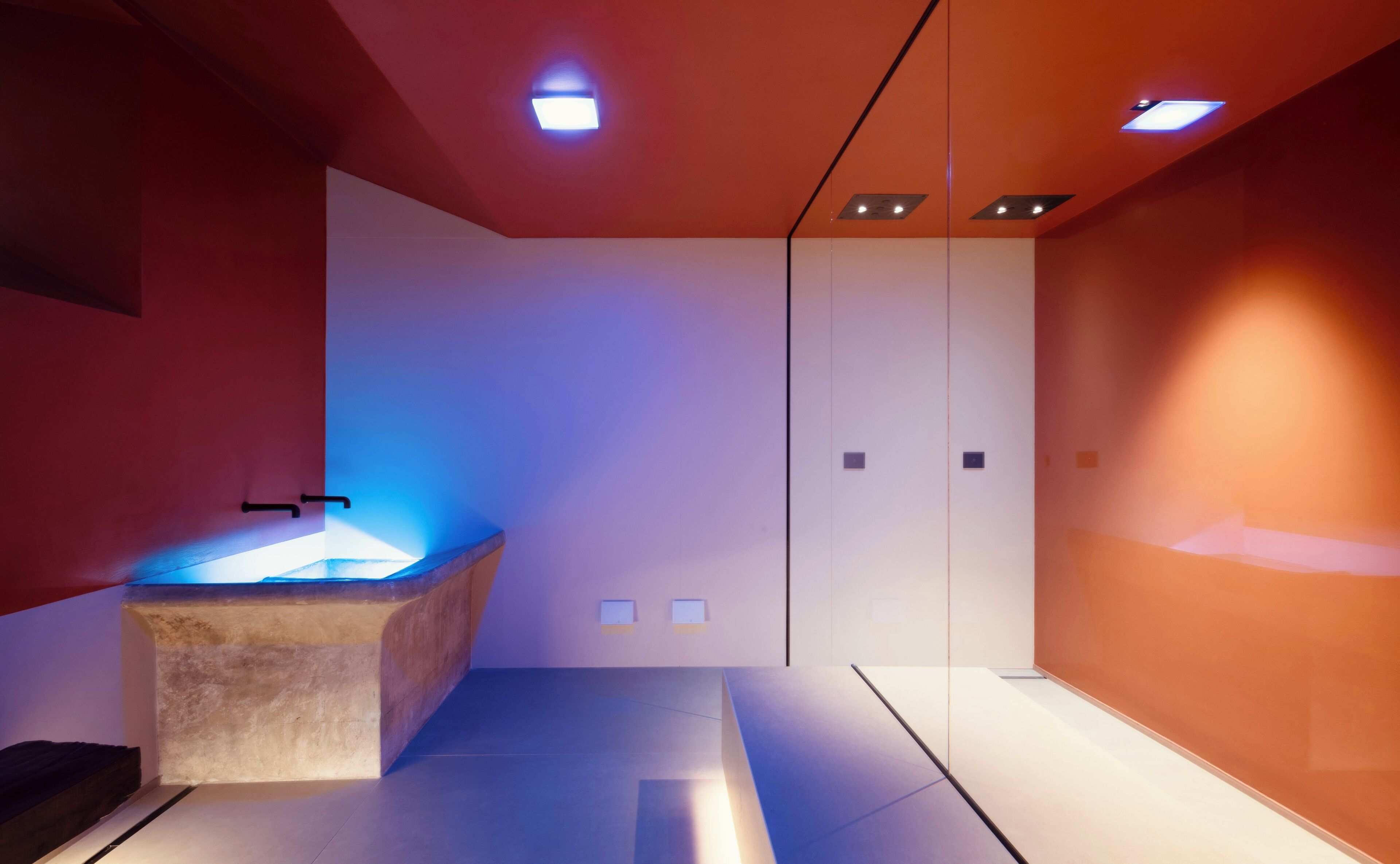 A modern bathroom with a central sink, recessed lighting, and a minimalist design.