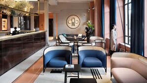 En moderne hotellobby med reception, siddeområde og et stort vindue.