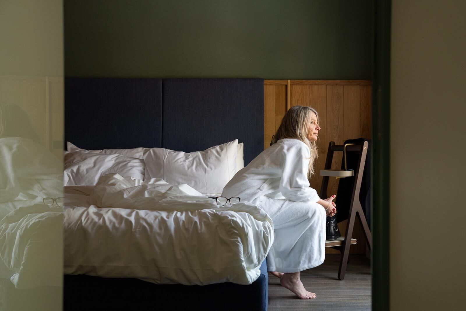 Ein Zimmer mit einem Bett, einem Holzstuhl und einem dunklen Kopfteil.