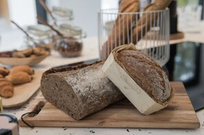 A loaf of bread on a wooden cutting board with a knife. - Salty Woods Lodge (Soustons)