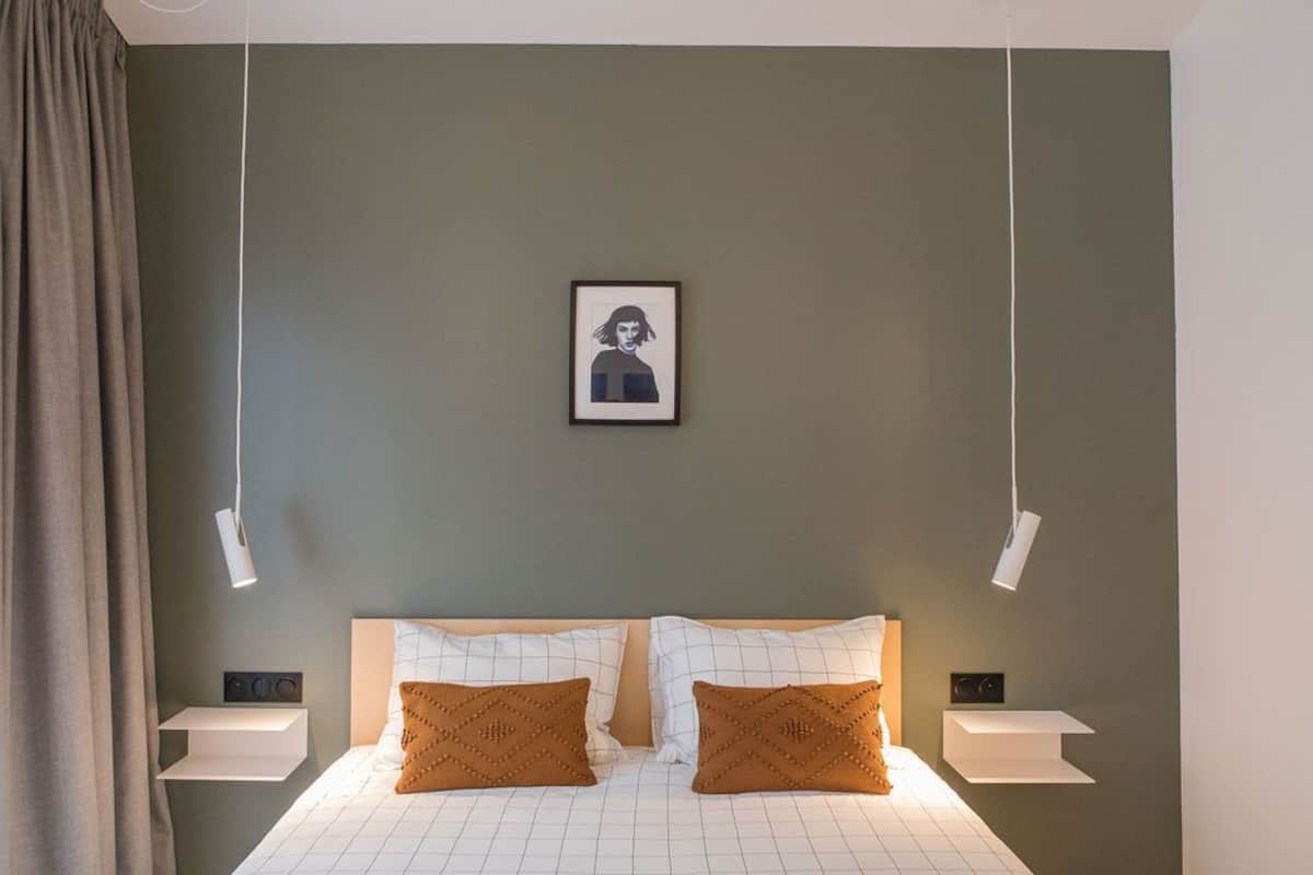 A modern bedroom with a bed, two pillows, a framed picture on the wall, and two bedside tables with lamps.
