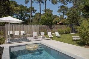 A backyard with a swimming pool, lounge chairs, and a wooden deck. - Salty Woods Lodge (Soustons)