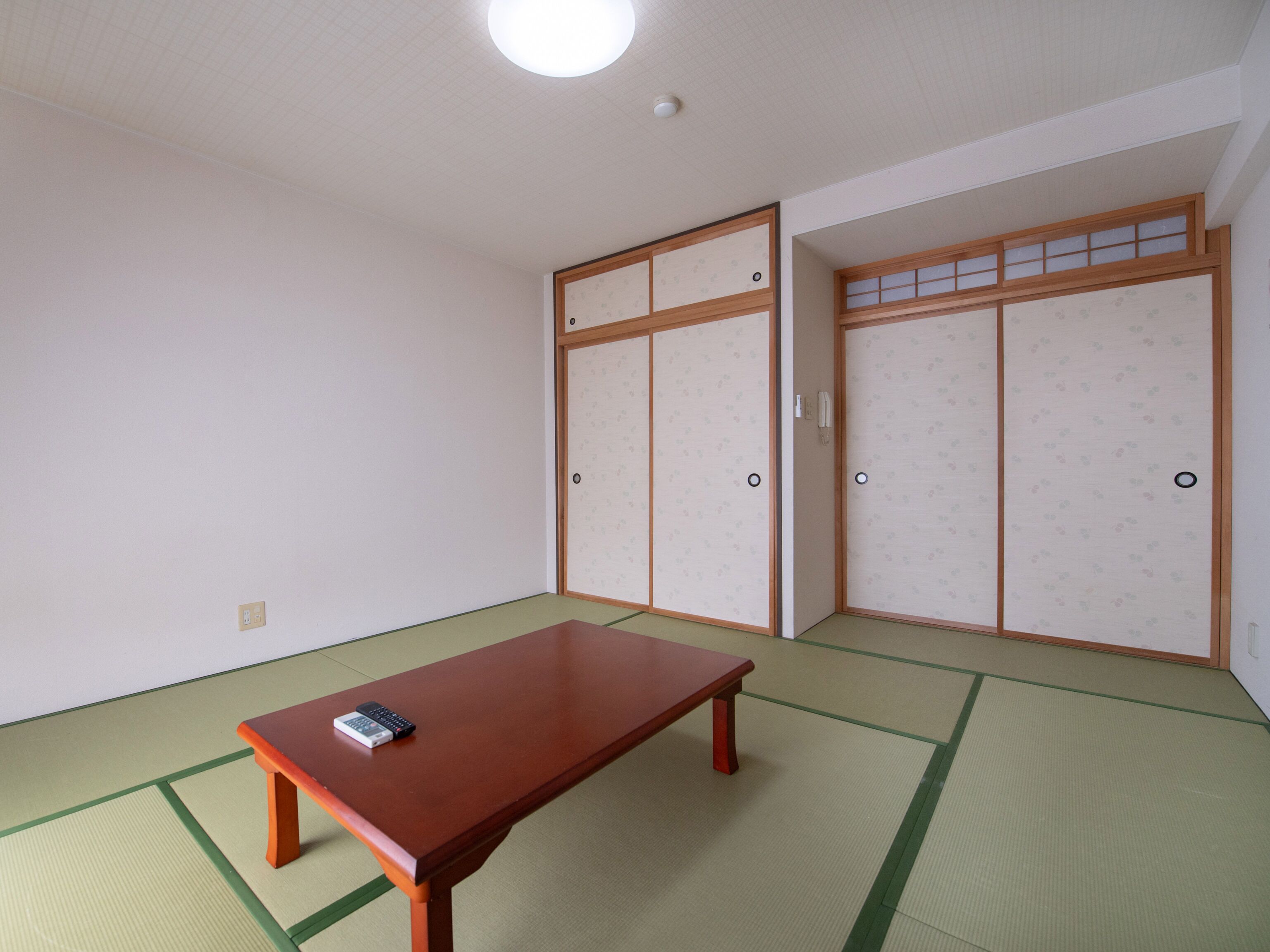 A room with tatami flooring, a wooden table, and traditional sliding doors.