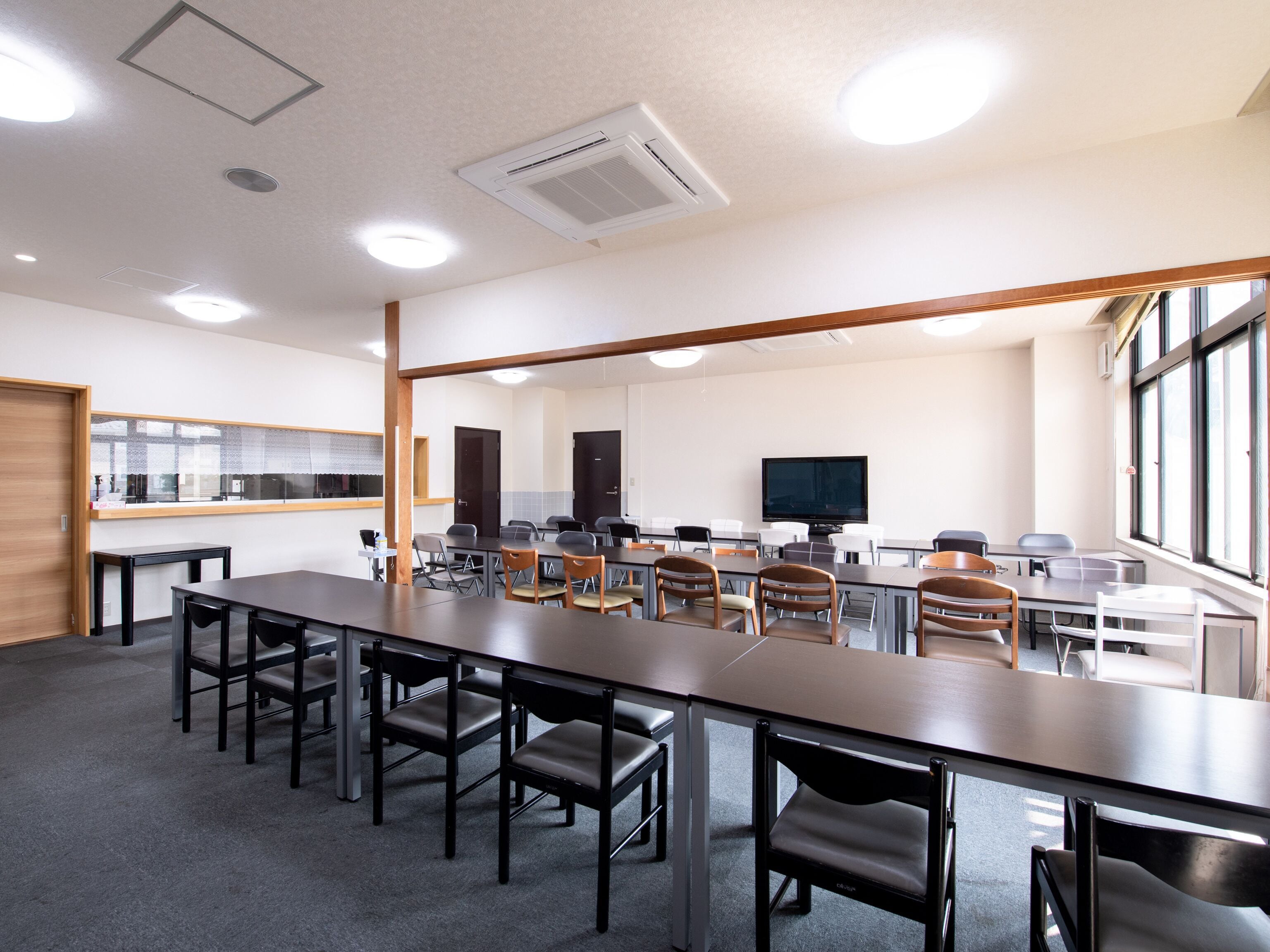 A conference room with a long table, multiple chairs, a television, and a window.