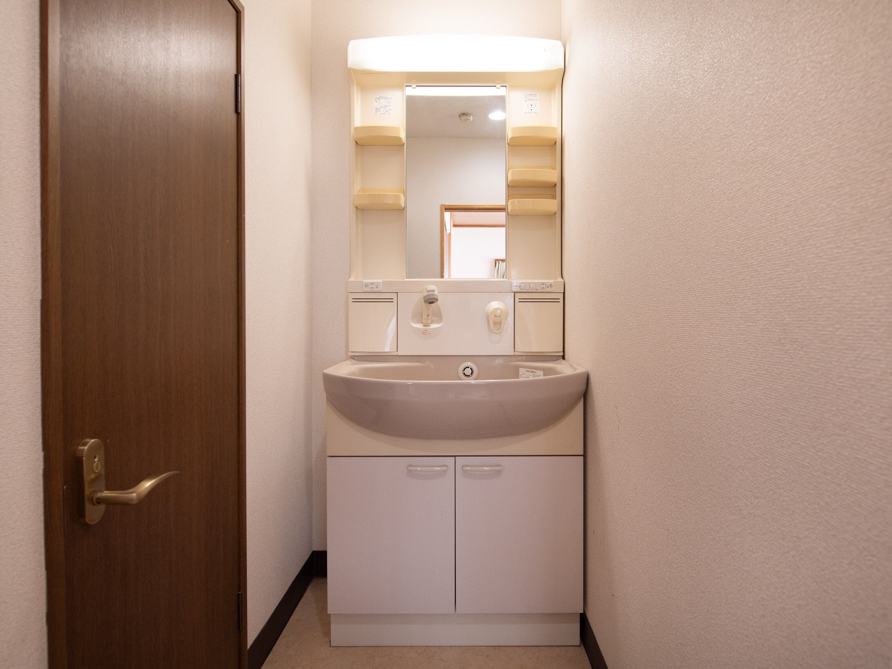 Un baño con lavamanos, espejo y armarios.