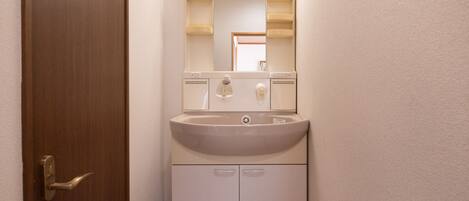Un baño con lavamanos, espejo y armarios.