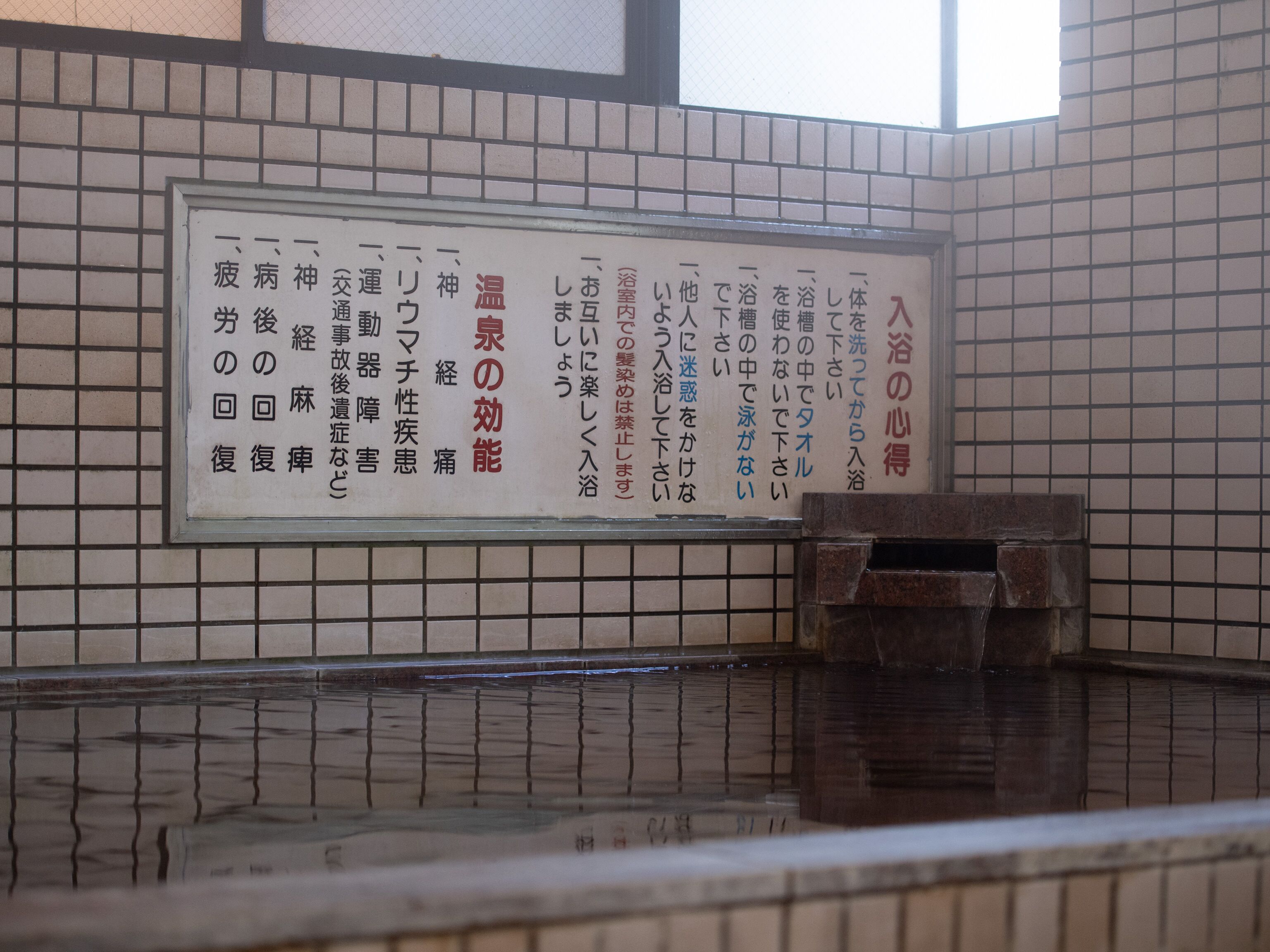 Una pared de azulejos con un letrero en japonés.