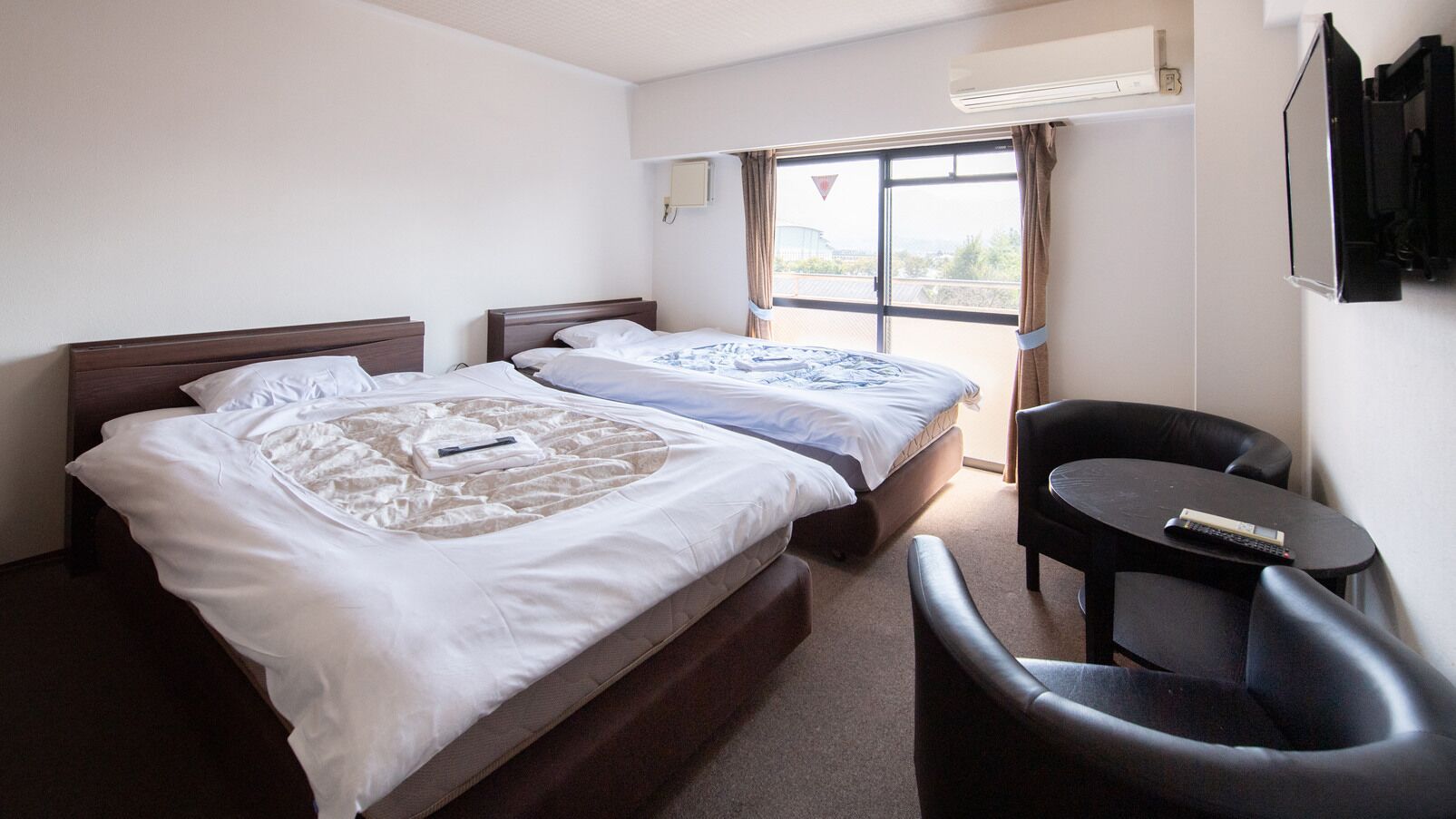 Habitación de hotel con dos camas, una mesita y una silla.