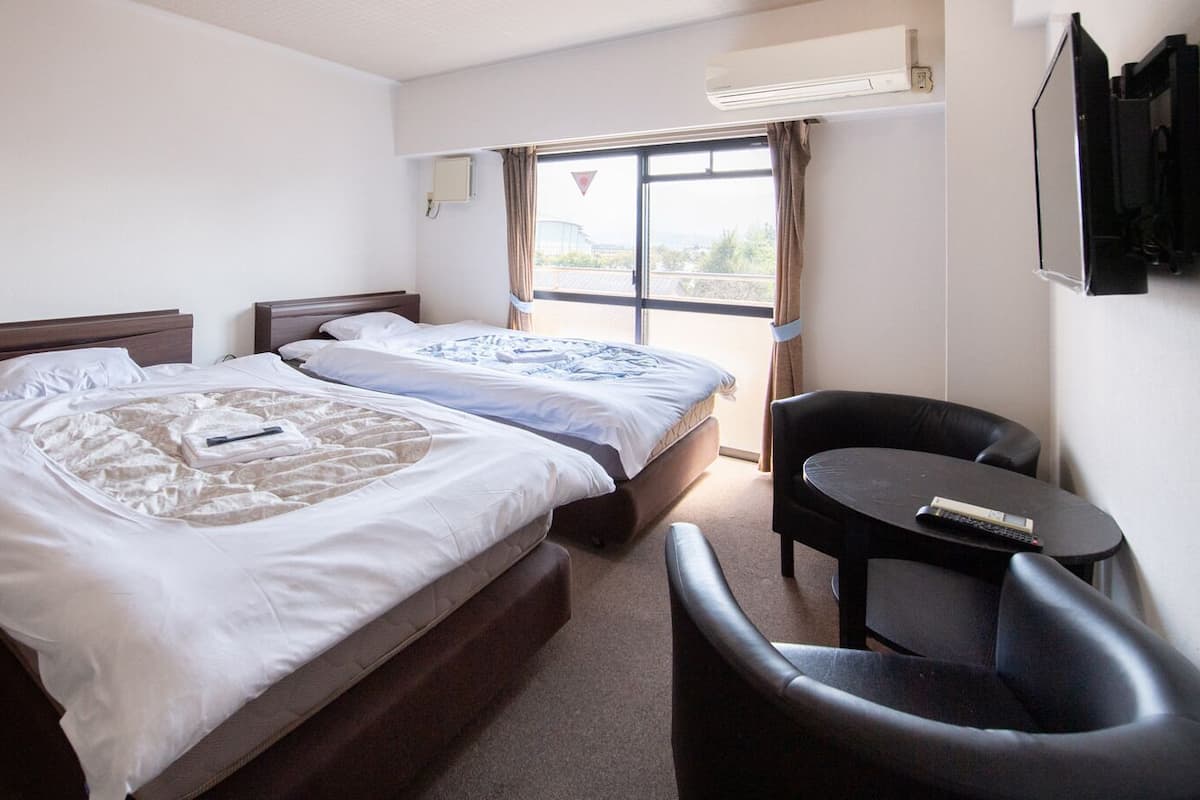 Habitación de hotel con dos camas, una mesita y una silla.