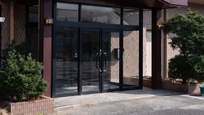 A building entrance with a brown awning and glass doors. - Tabist Hotel Yamashiro Onsen (Kofu)