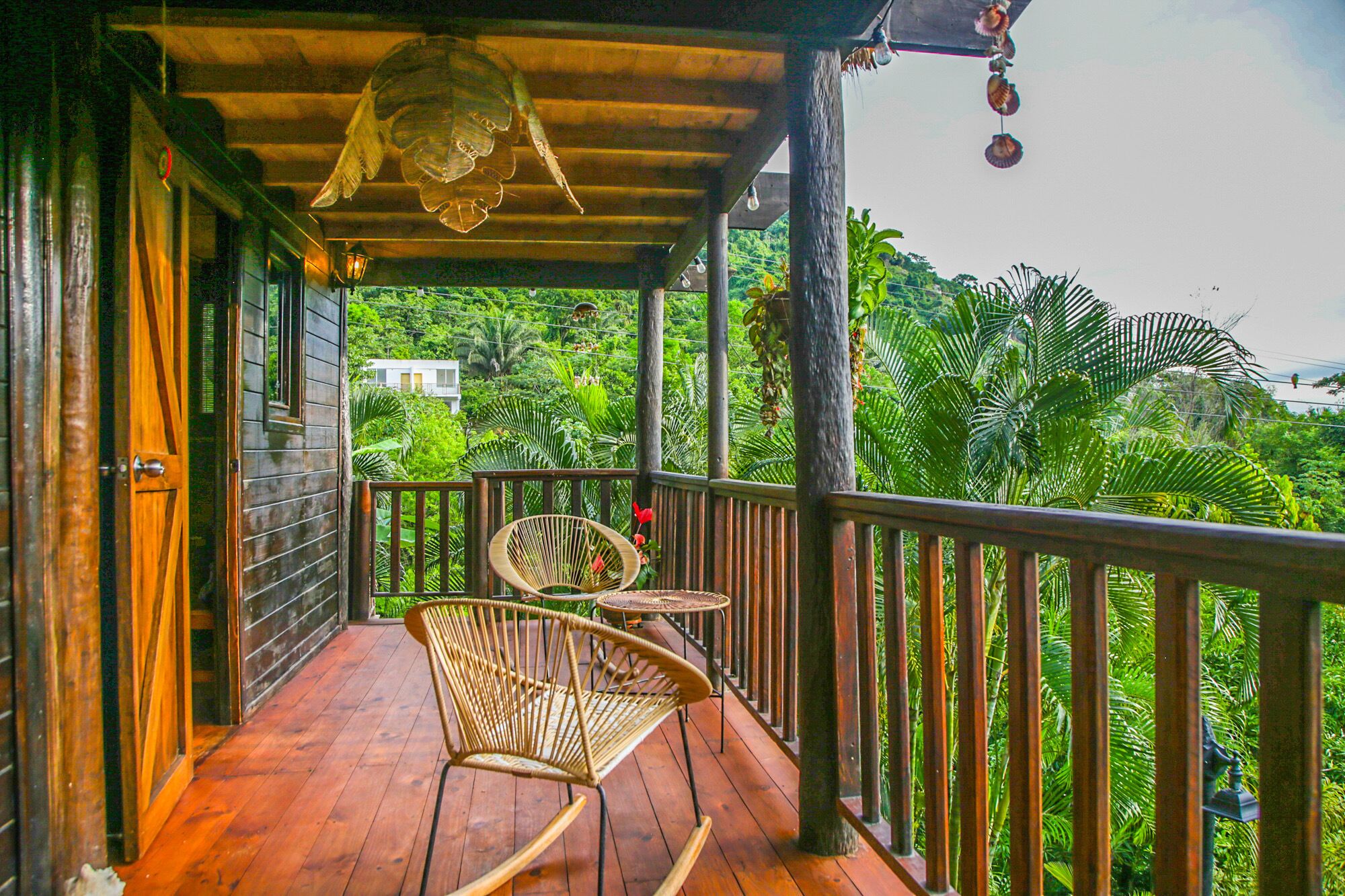 A wooden porch with a wooden railing, a wicker chair, and a small table.