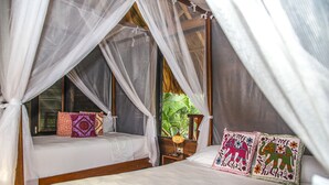 A room with a bed under a canopy, a nightstand with a lamp, and a window with blinds. - Villa tayrona (Santa Marta)