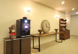 A room with a vintage telephone, a modern coffee machine, a large wall clock, and a wooden cabinet with decorative items. - Time Square Hotel (Yangsan)