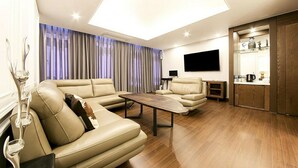 A modern living room with a sectional sofa, a coffee table, and a flat-screen TV mounted on the wall. - Time Square Hotel (Yangsan)