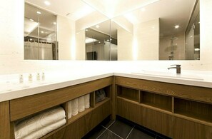 A modern bathroom with a large mirror, two sinks, and wooden cabinetry. - Time Square Hotel (Yangsan)