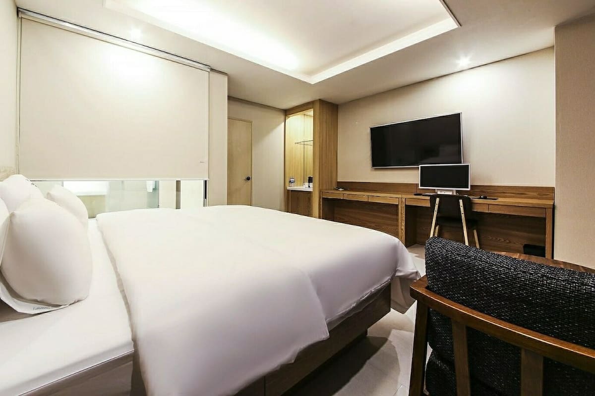 A hotel room with a large bed, a flat-screen TV, a desk, and a chair.