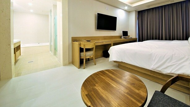 A hotel room with a bed, a desk, a chair, a TV, and a bathroom. - Time Square Hotel (Yangsan)