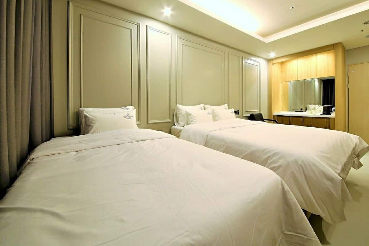 A hotel room with two beds, a bathroom, and a desk with a mirror.
