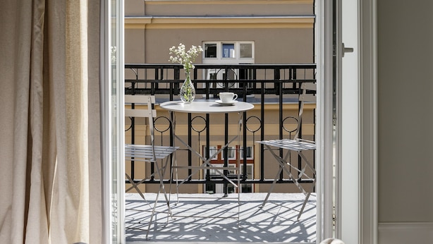 An open balcony with a view of a building's roof and a table with chairs. - Lwowska Studios - STAYINWARSAW (Warsaw)