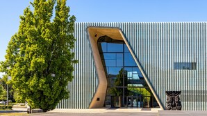 A modern building with a unique angular design, large glass windows, and a tree in front. - Lwowska Studios - STAYINWARSAW (Warsaw)