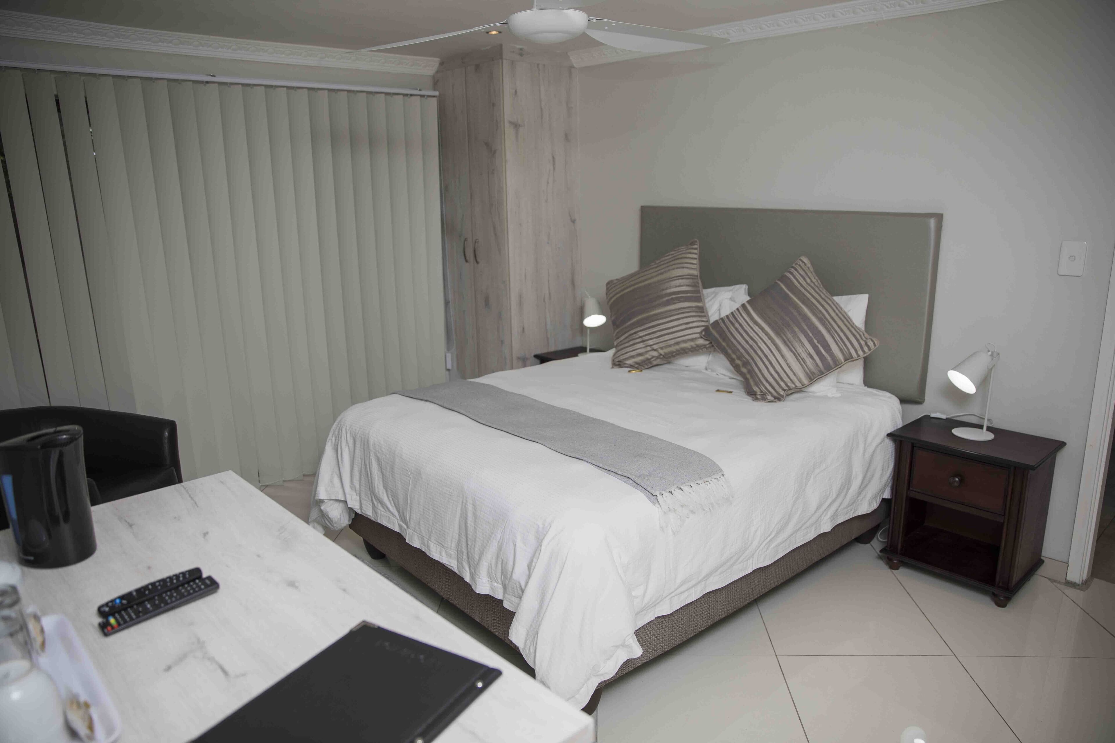Ein Hotelzimmer mit Bett, Nachttischen, Schreibtisch und Stuhl.
