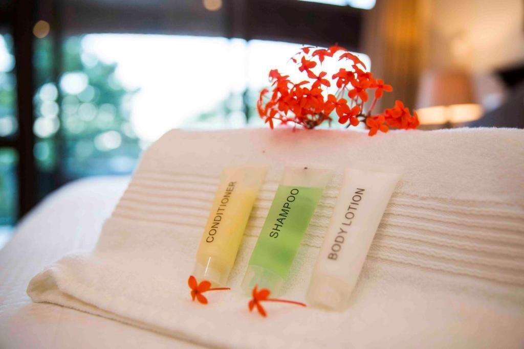 A neatly folded towel with three toiletry items: conditioner, shampoo, and body lotion.