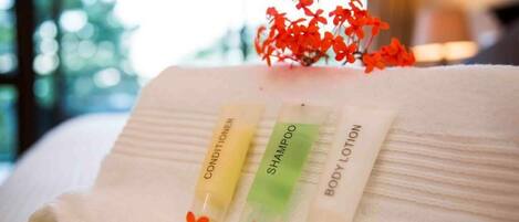 A neatly folded towel with three toiletry items: conditioner, shampoo, and body lotion.