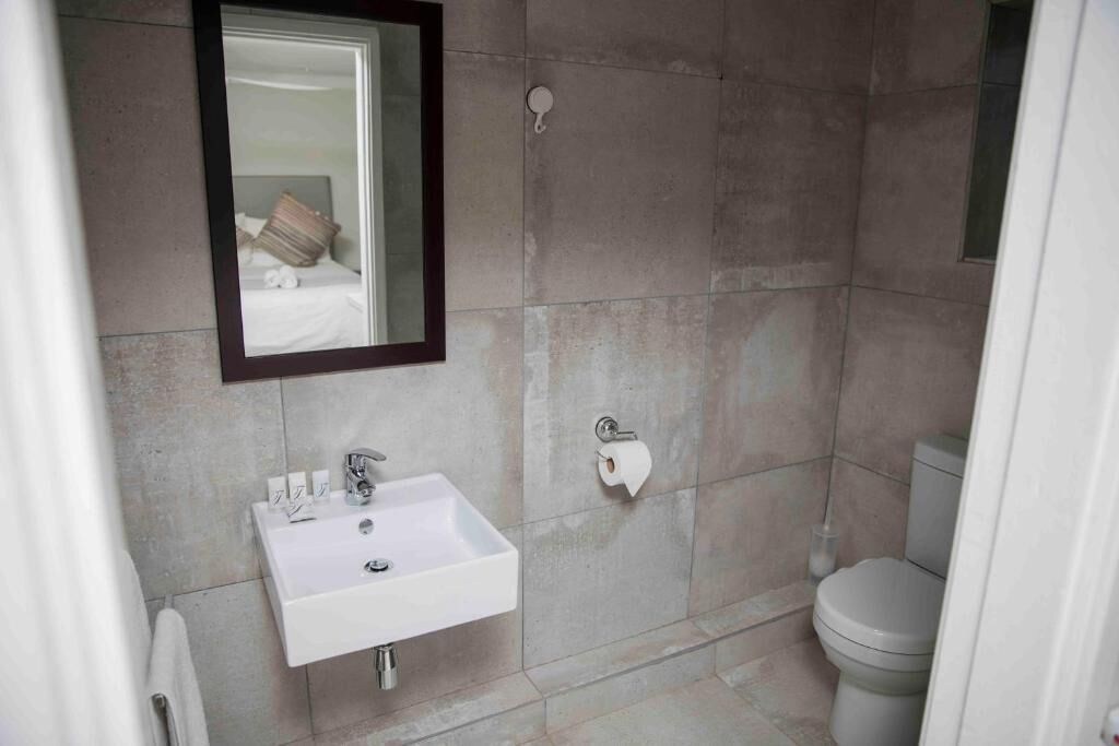 A bathroom with a white sink, mirror, and toilet.