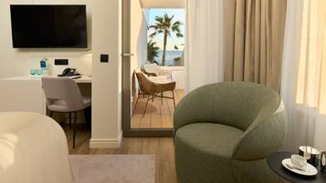 Une chambre d’hôtel moderne dotée d’un balcon, d’une télévision à écran plat, d’un bureau avec un téléphone et d’un coin salon confortable comprenant un fauteuil vert et une petite table avec une tasse et une soucoupe.