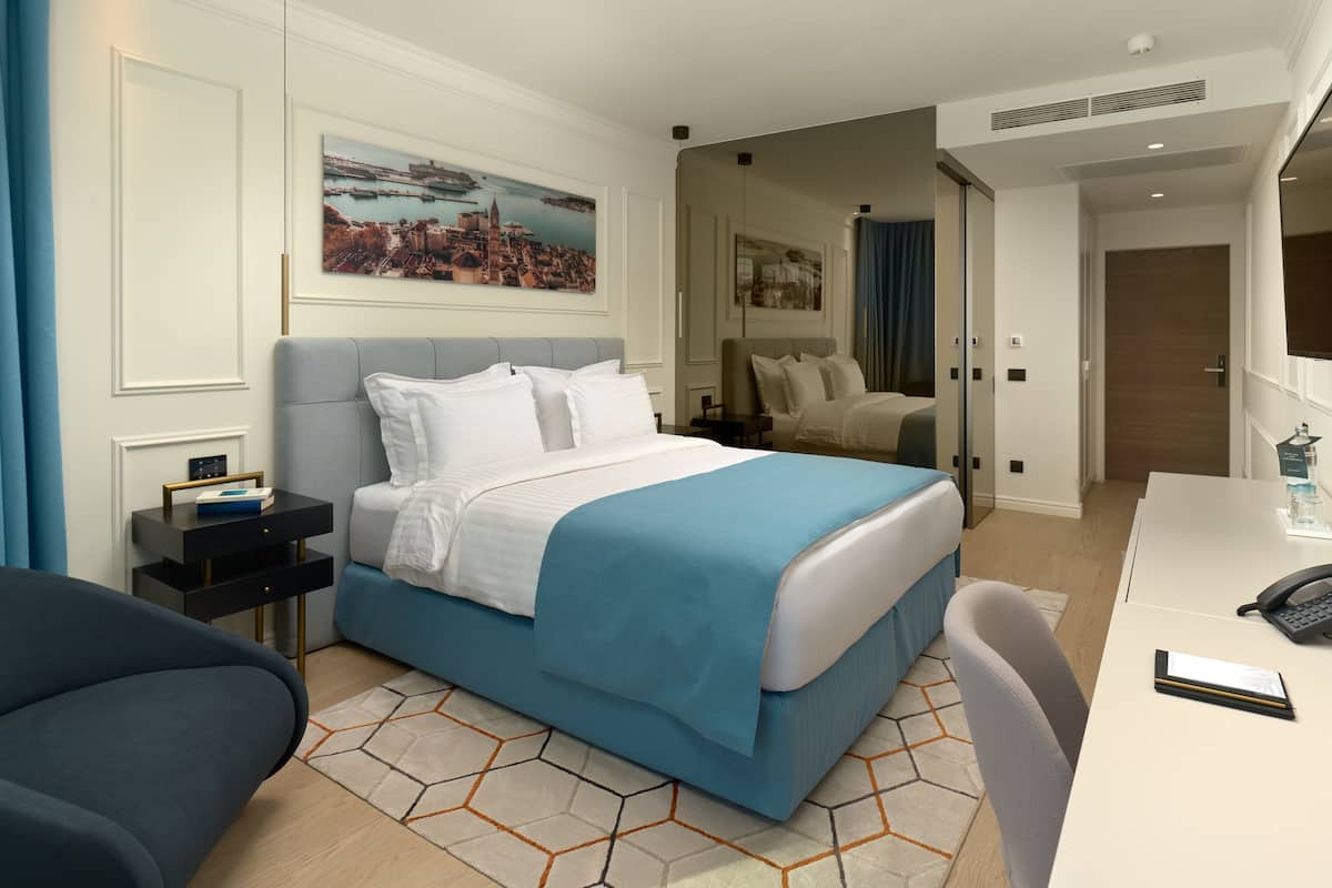 A hotel room with a large bed, a desk with a telephone, and a chair.