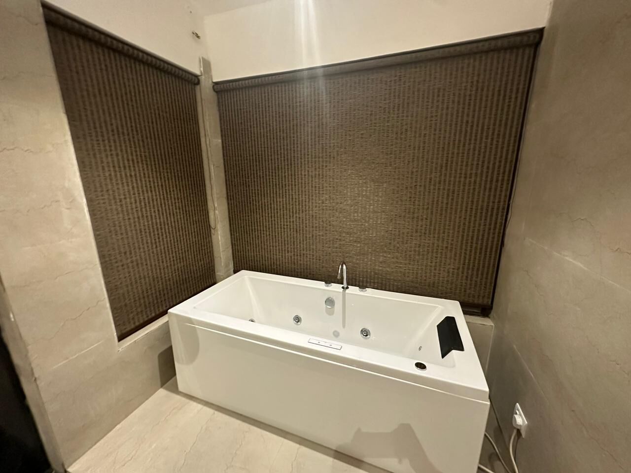 A modern bathroom with a rectangular bathtub, a shower area, and a textured wall panel.