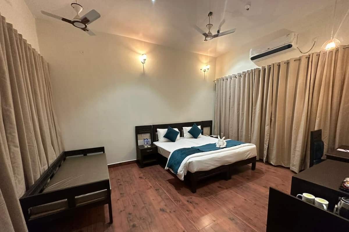 Une chambre d’hôtel équipée d’un lit, de tables de chevet, d’un bureau, d’une chaise, de rideaux et de ventilateurs de plafond.