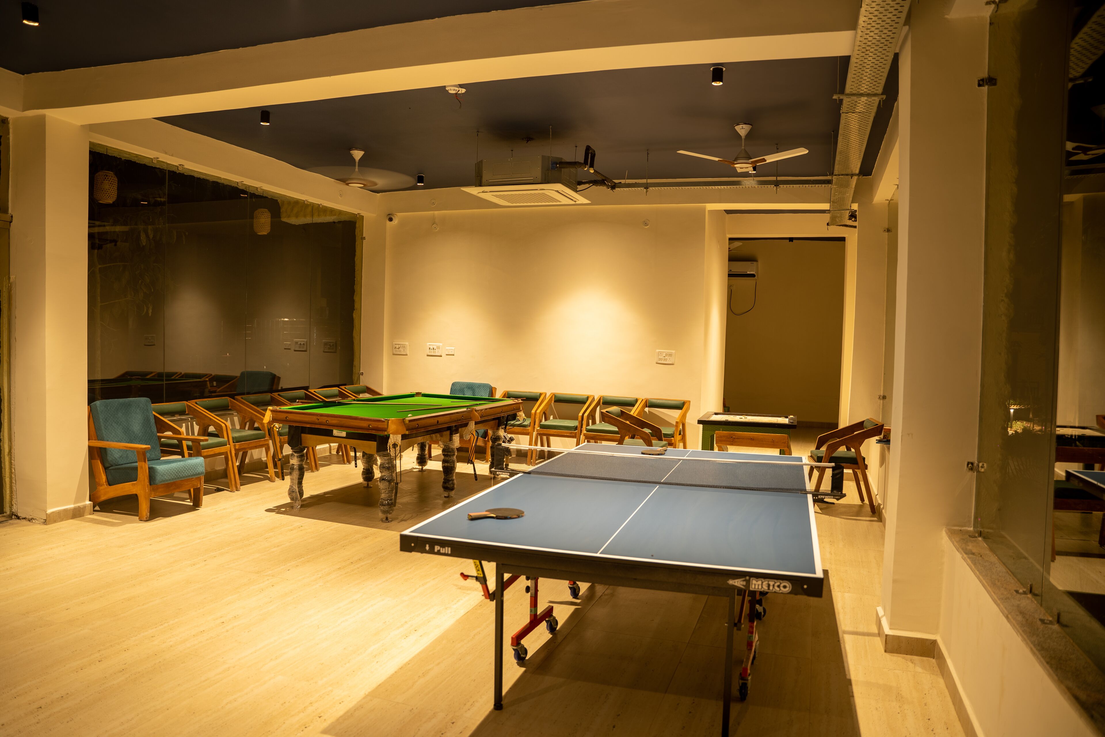 Een kamer met een tafeltennistafel, een pooltafel en diverse stoelen.