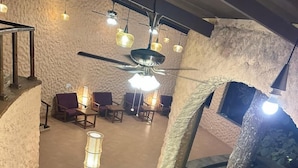 Un espace patio intérieur avec des murs en pierre, des meubles en bois et des lampes suspendues.