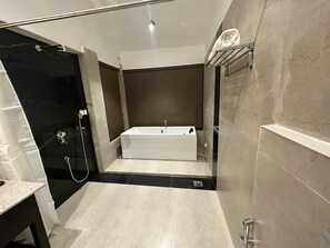 Un baño moderno con una bañera independiente, ducha con cerramiento de vidrio y suelo de mármol.