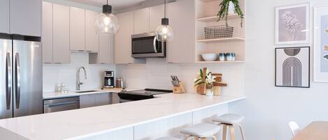 A modern kitchen with a central island, bar stools, a microwave, and a TV.