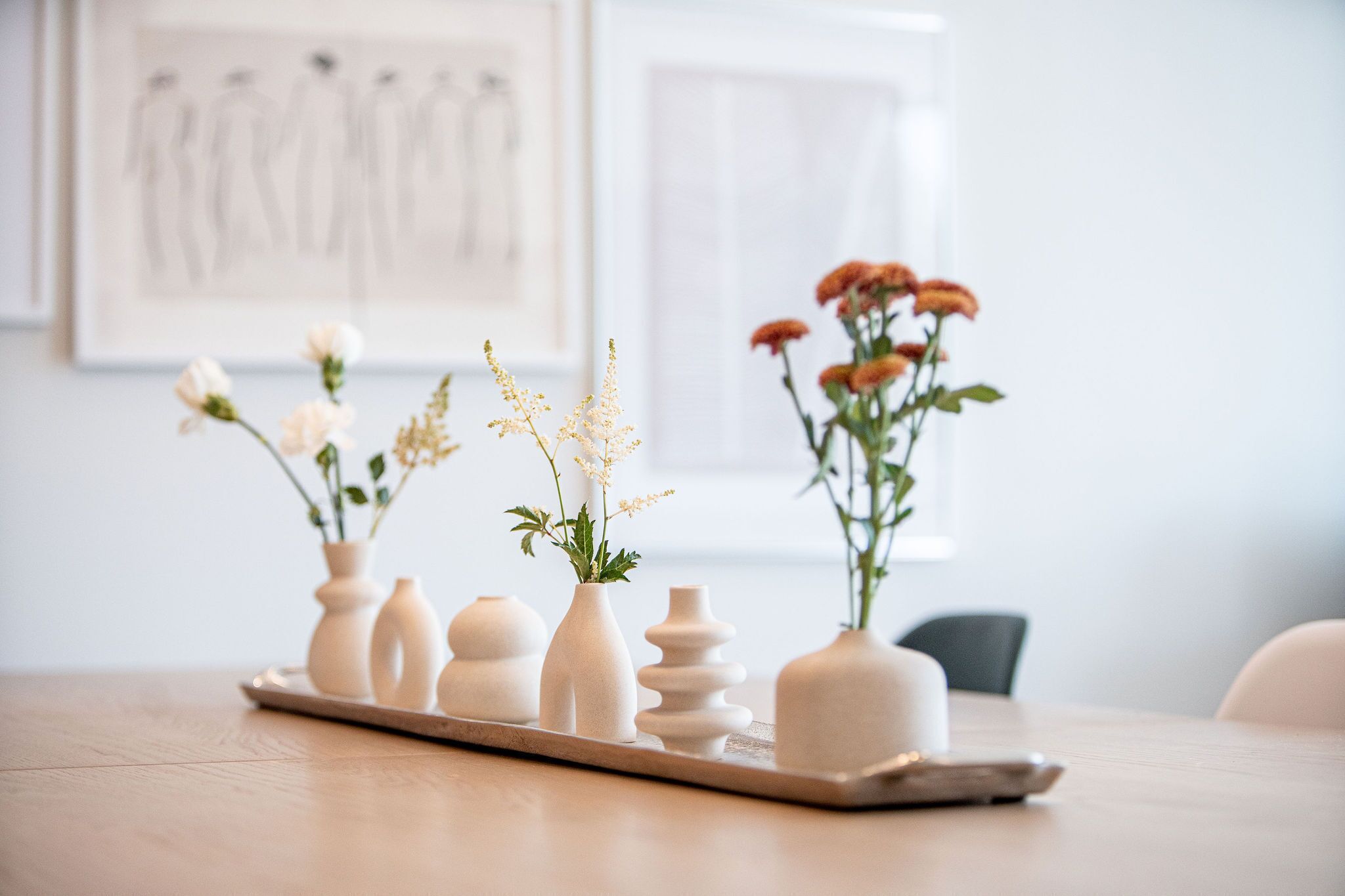 Eine Schale mit fünf Blumenvasen auf einem Holztisch.