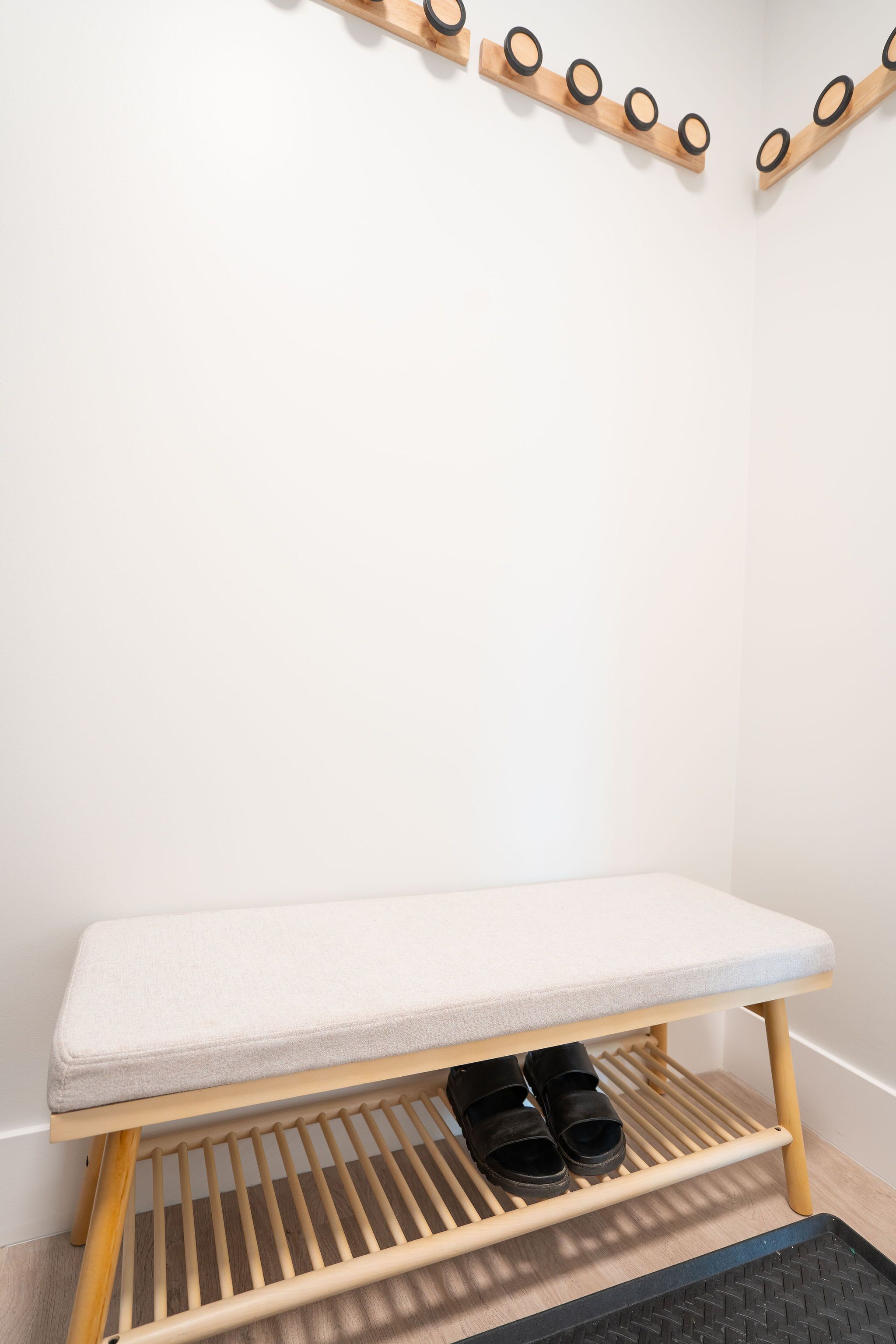 A wooden bench with a cushioned seat and a shoe rack underneath.
