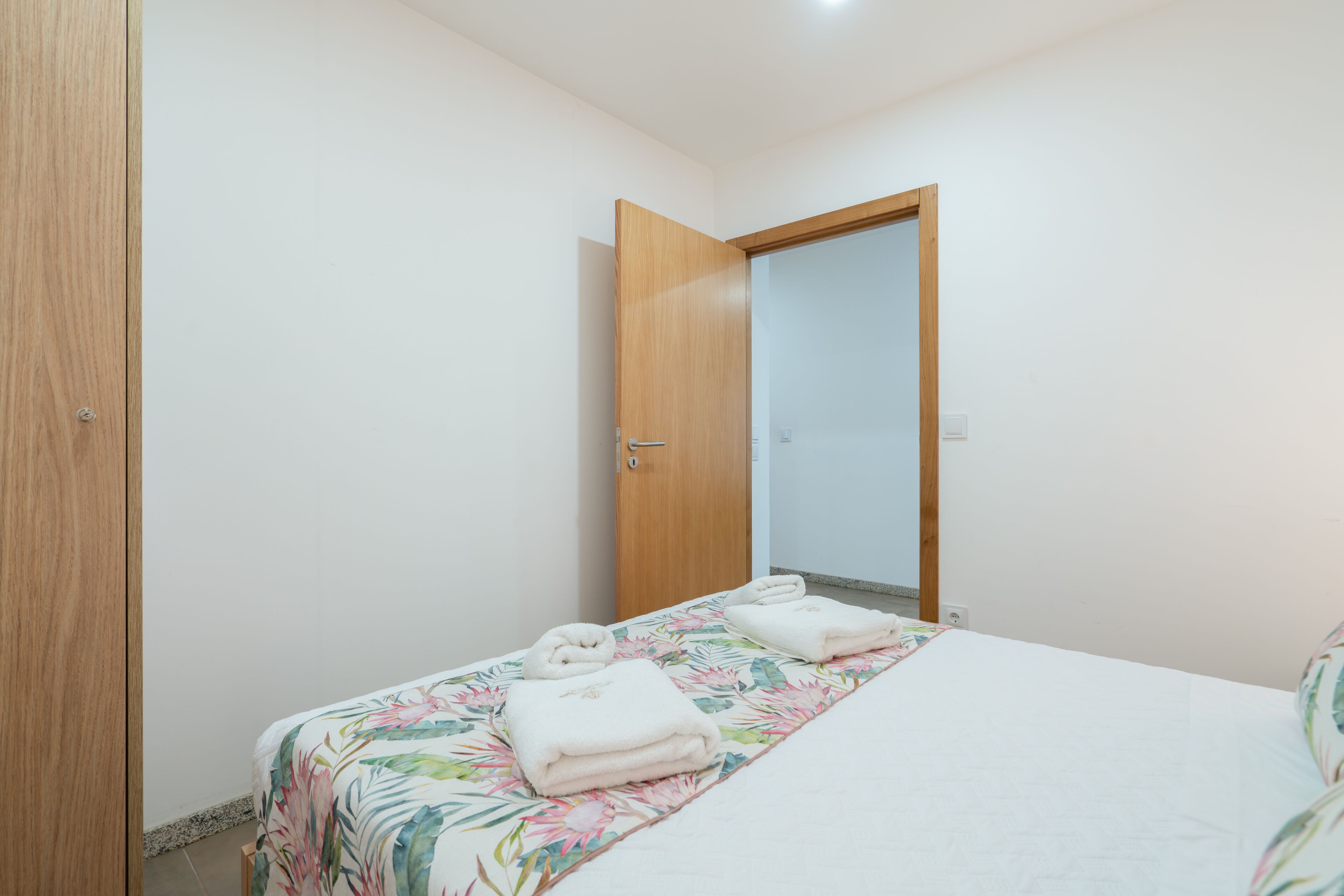 Un dormitorio con cama, puerta de madera y espejo.