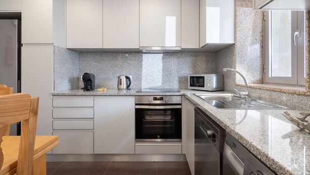 A modern kitchen with white cabinets, a granite countertop, a built-in oven, a microwave, and a stainless steel sink. - Casas da Petisqueira 61 - Paredes-Oporto (Paredes)