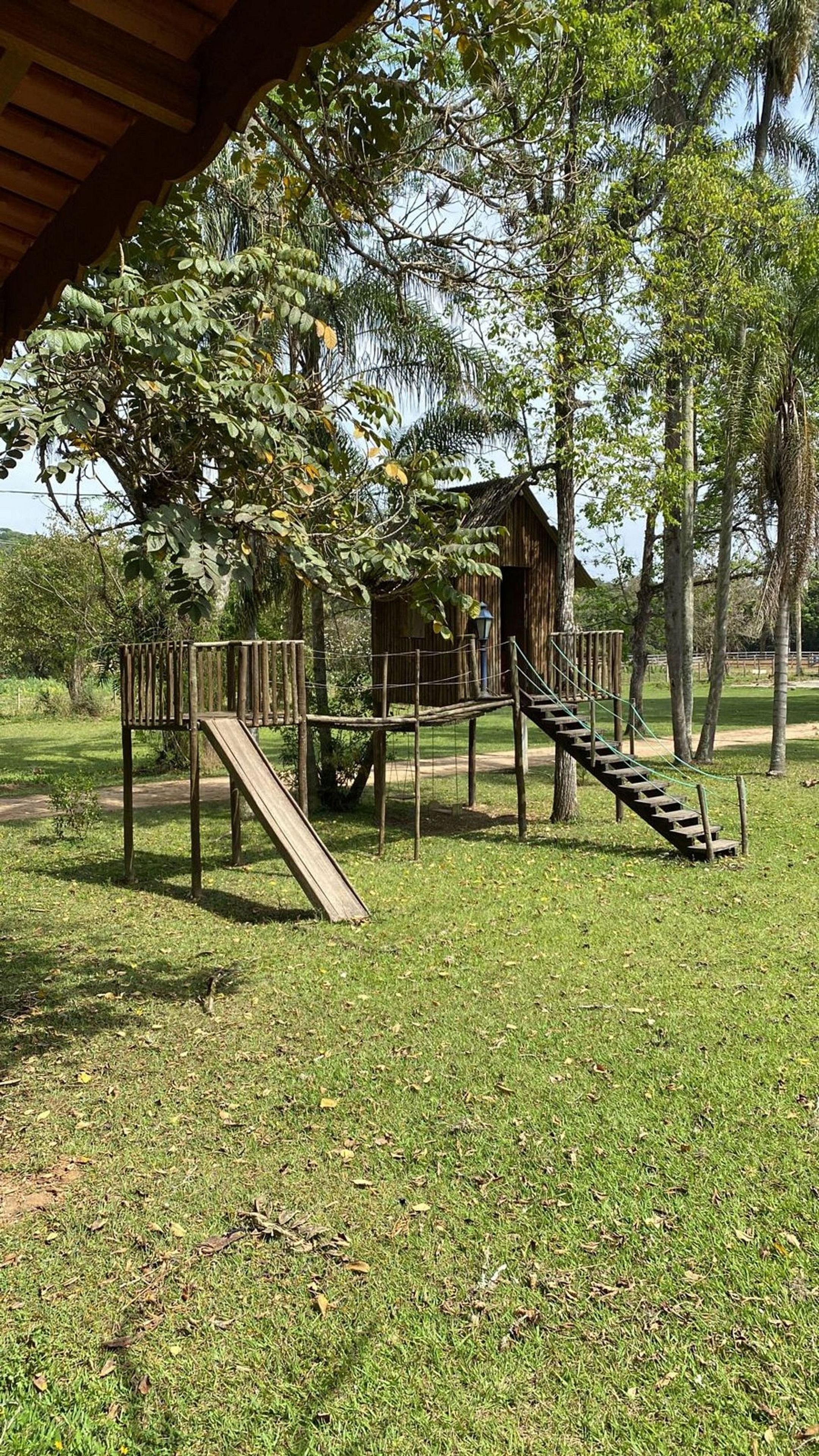 A playground with a slide, a rope bridge, and a wooden structure.