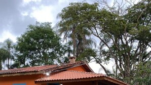 A house with a red roof, a porch with wooden furniture, and a well-maintained lawn. - Magnífico Rancho em Jarinu (Jarinu)
