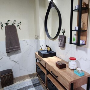 A bathroom with a wooden vanity, a black sink, a mirror, and a shelf with toiletries. - Magnífico Rancho em Jarinu (Jarinu)